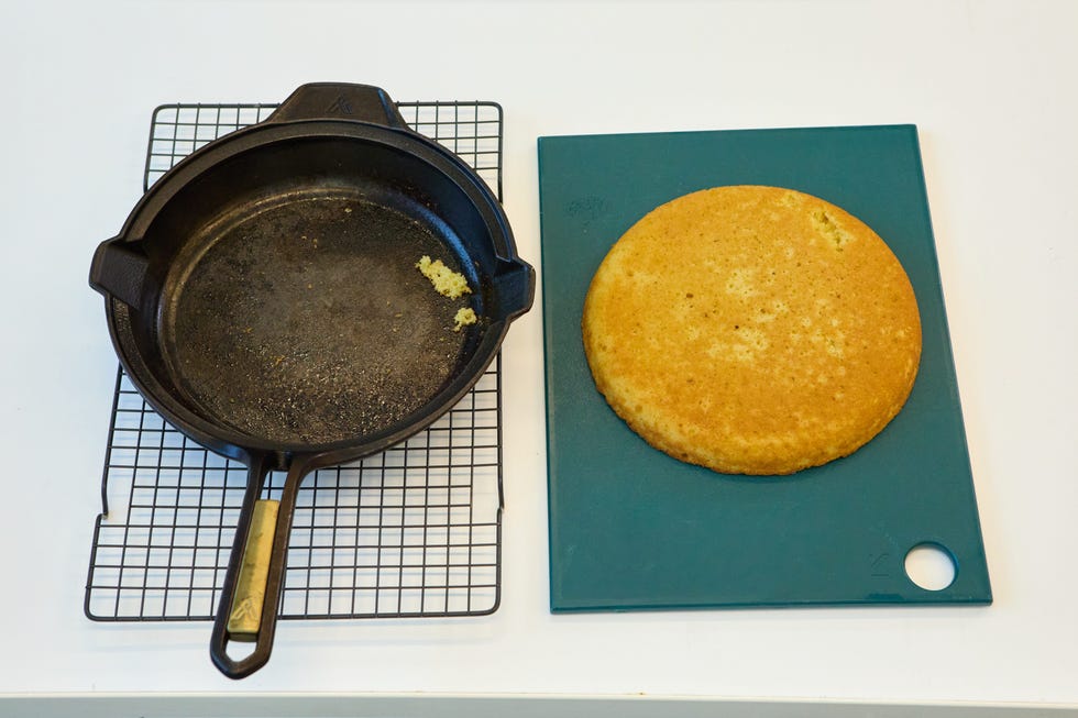 overhead shot of a cast iron pan next to the cornbread that was baked in it. the pan has one little piece of cornbread stuck to it but is mostly empty, showing a successful release
