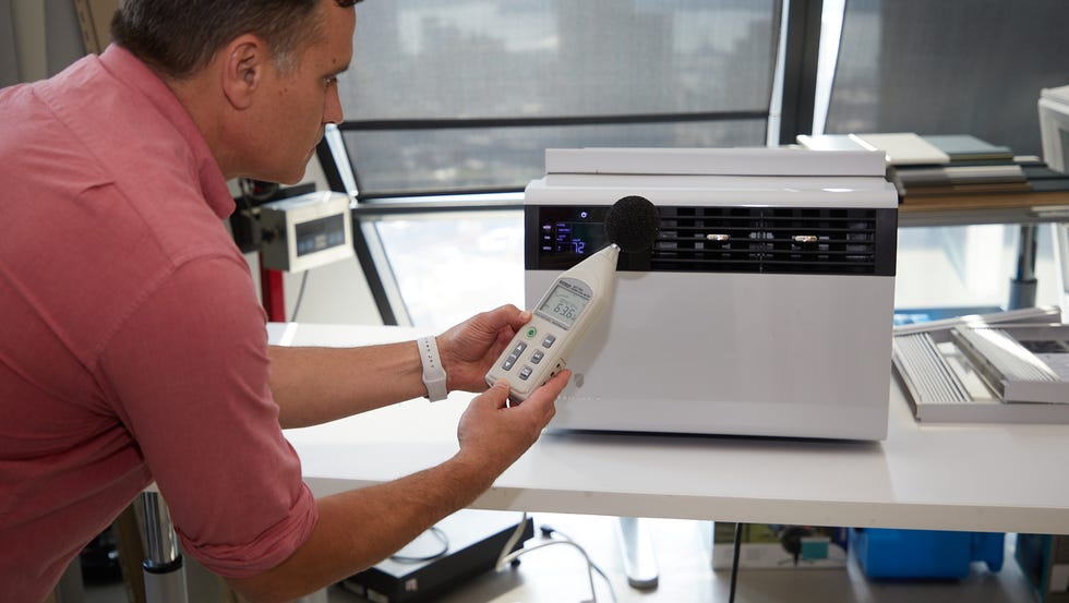 portable air conditioner versus window air conditioner a man using a sound meter on an air conditioner