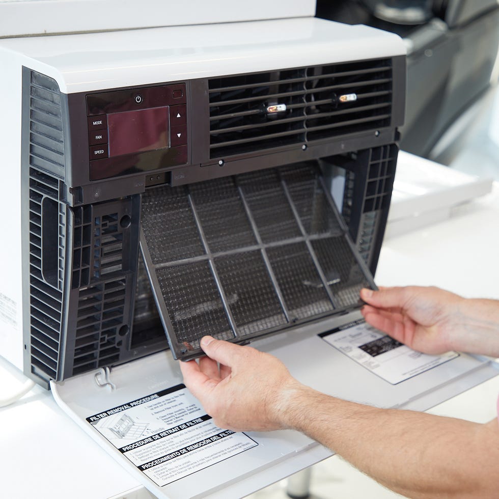 window ac test a man removing a filter from an air conditioner