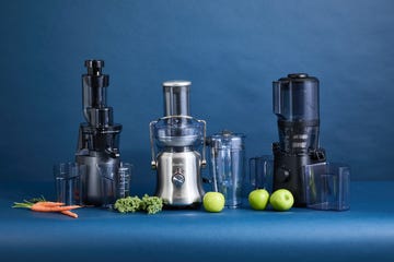 three juicers side by side with carrots, kale and apples on the counter