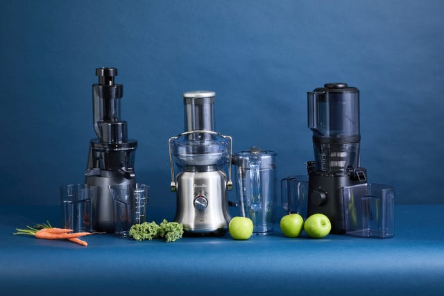 three juicers side by side with carrots, kale and apples on the counter