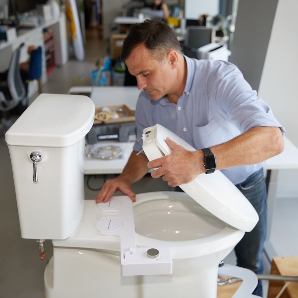 an expert at the good housekeeping institute installs a bidet seat as part of a review