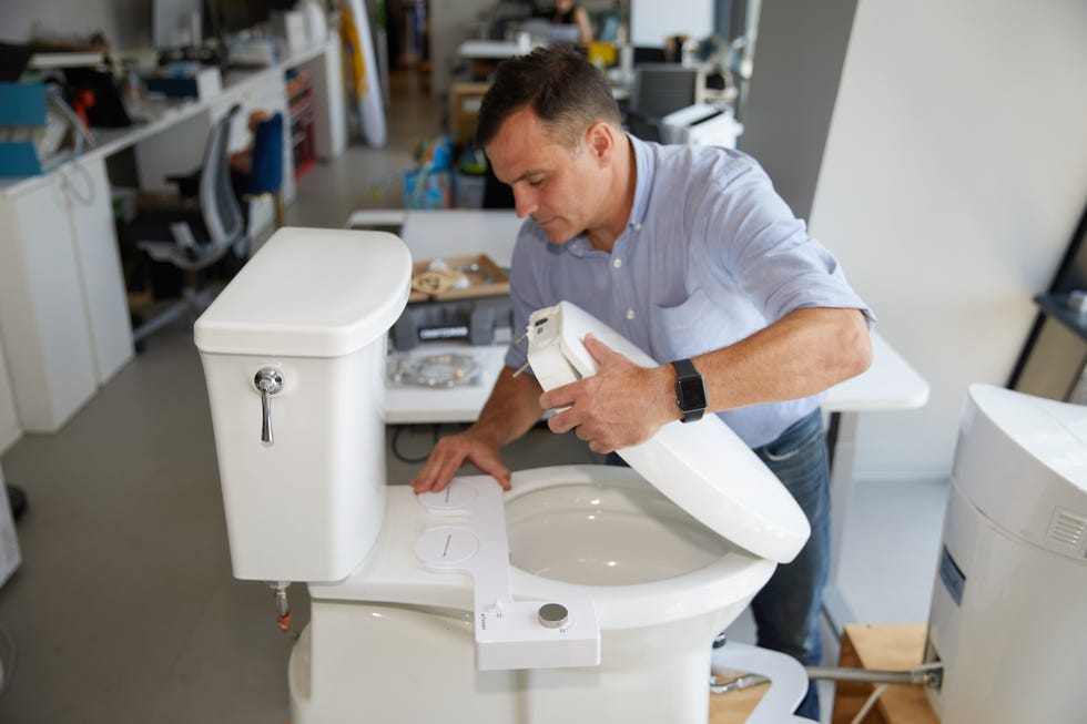 an expert at the good housekeeping institute installs a bidet seat as part of a review