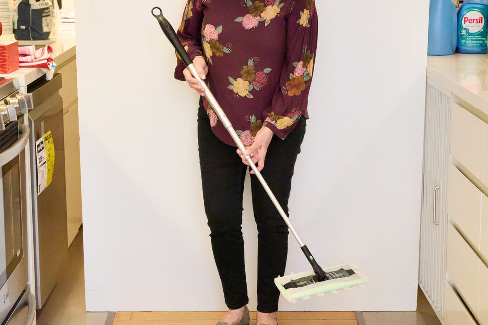 woman holding the swiffer sweep & mop deluxe 2 in 1 floor mopping and sweeping kit