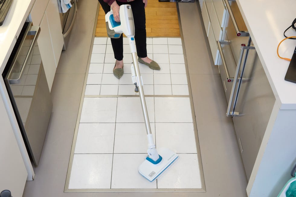 white and blue steam mop on a white tiled floor