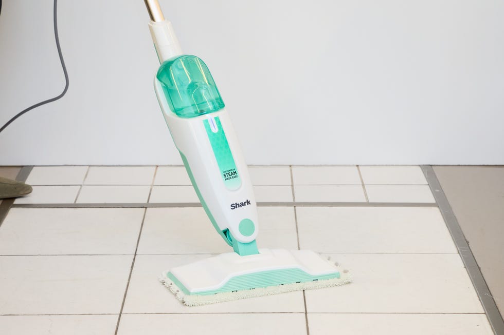 white and green steam mop on a white tiled floor