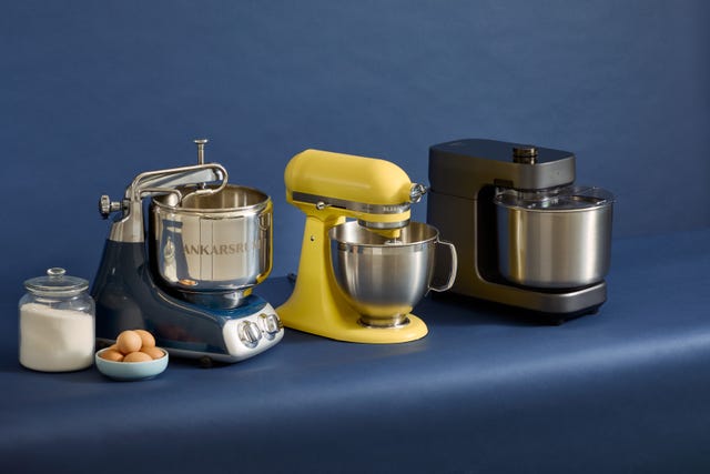 three stand mixers in various colors with a jar of sugar and eggs next to them