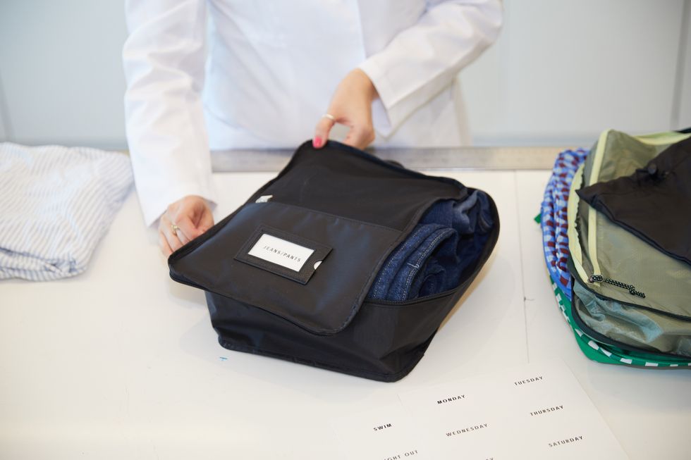 an analyst testing black beis packing cubes with labels of what is inside, good housekeeping's best packing cubes