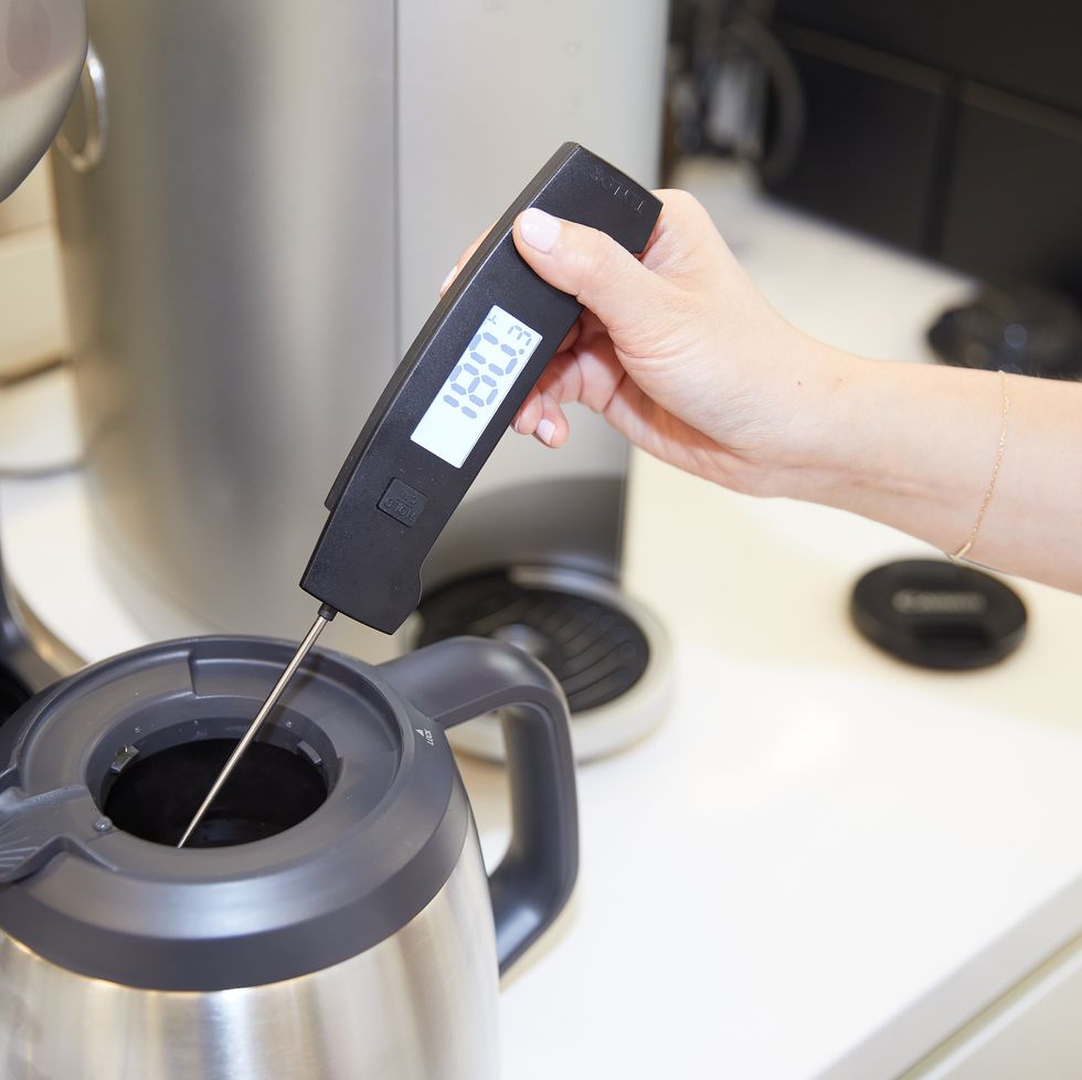 taking the temperature of a pot of coffee using a thermometer