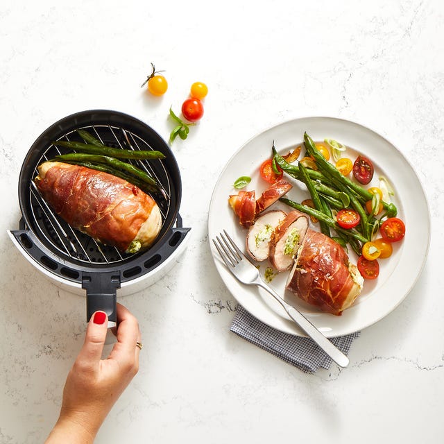 a hand holding a knife over a plate of chicken