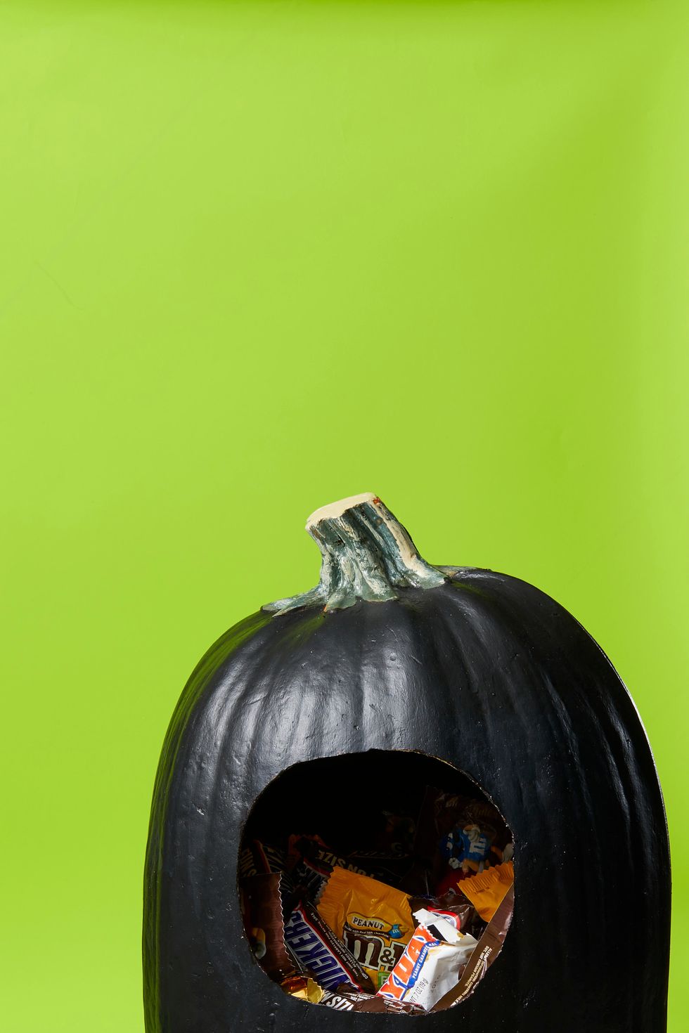pumpkin carving ideas, black pumpkin with a hole inside filled with candy