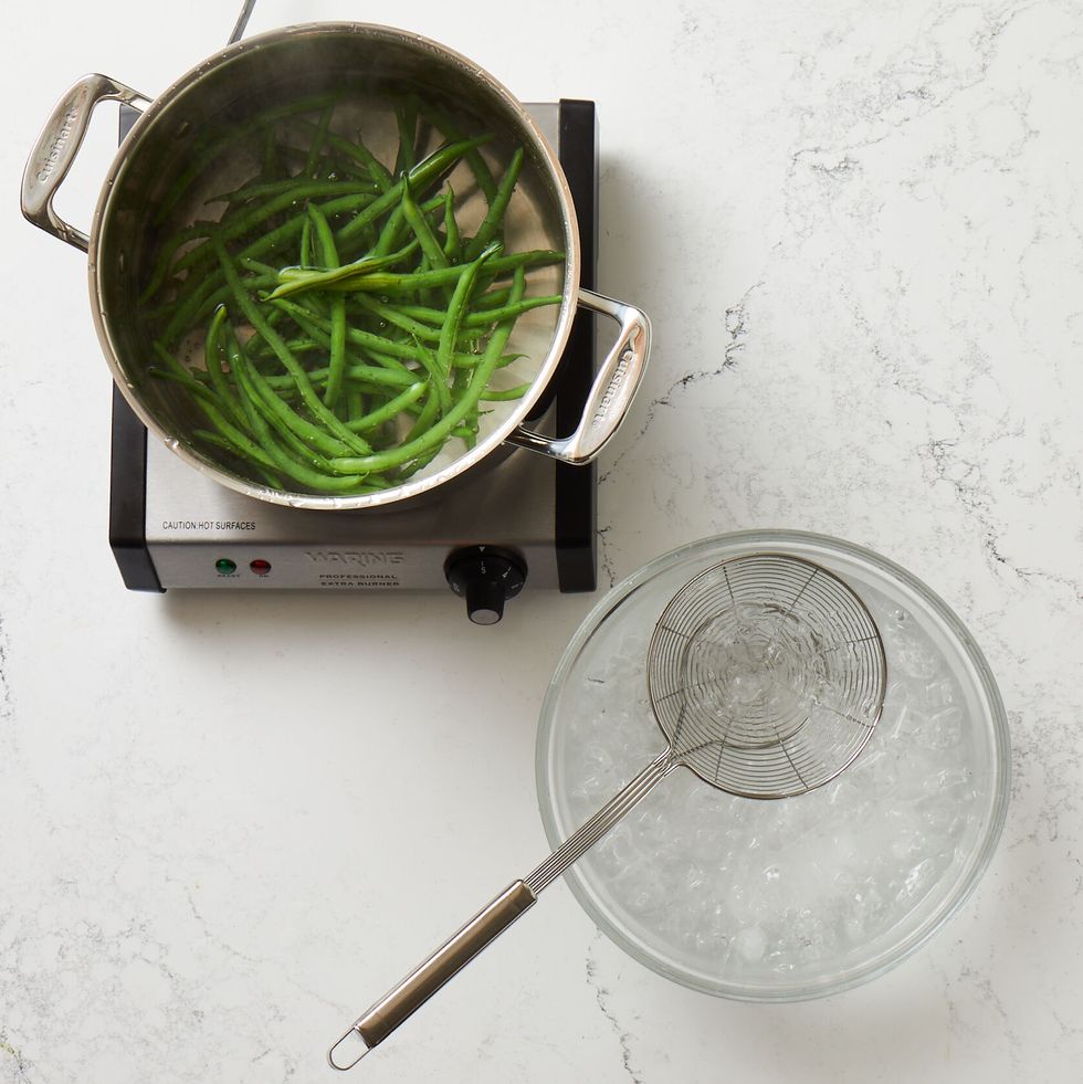 blanching green beans in a pot of boiling water