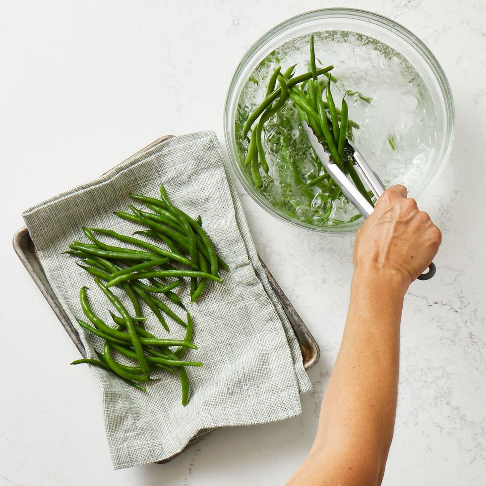 transferring blanched green beans to a towel lined pan