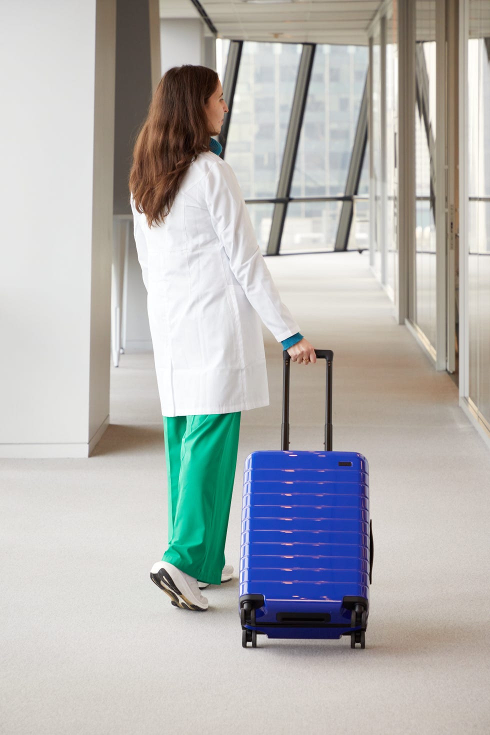 a good housekeeping analyst testing an away suitcase by rolling it in a hallway, good housekeeping's away luggage review