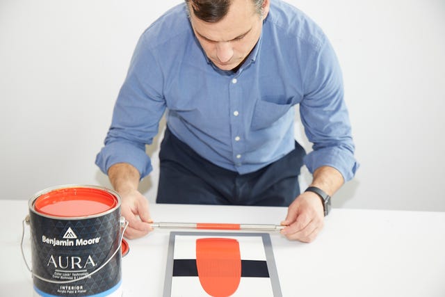 a tester applies paint with a metal applicator to opacity cards