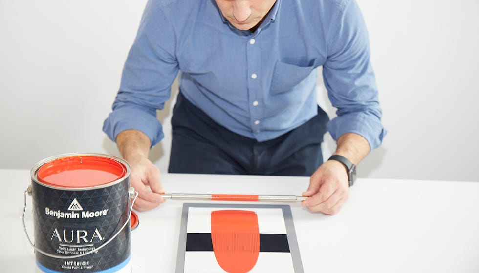 a tester applies paint with a metal applicator to opacity cards