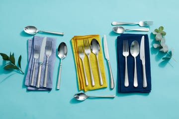 silver flatware sets on different color napkins on a blue background