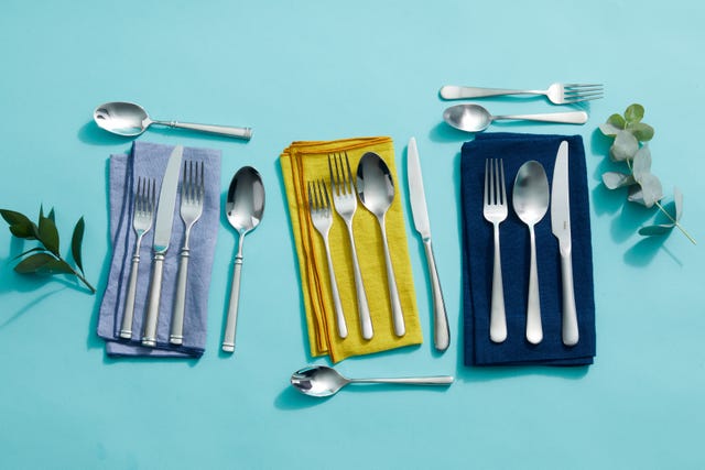 silver flatware sets on different color napkins on a blue background