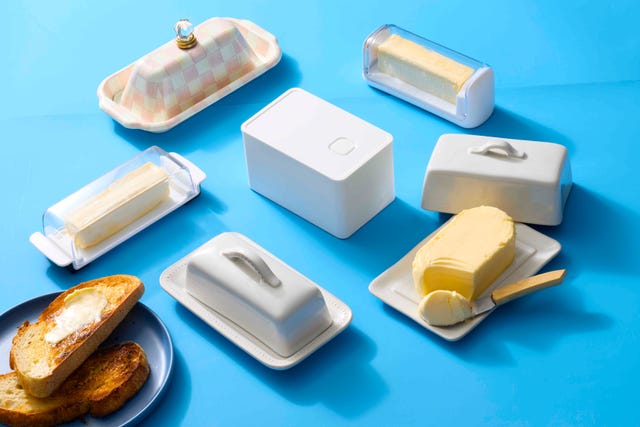a collection of butter dishes and butter crocks with sticks of butter on a blue background