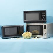 three microwaves with a bowl of popcorn