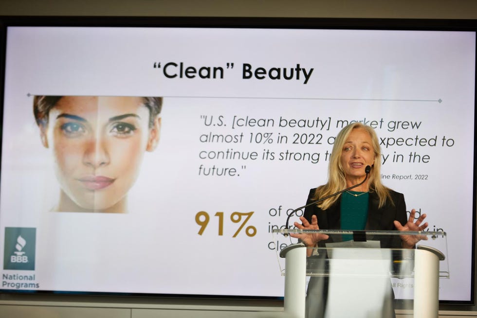 speaker laura brett standing behind a podium in front of a slideshow on a slide about clean beauty claims