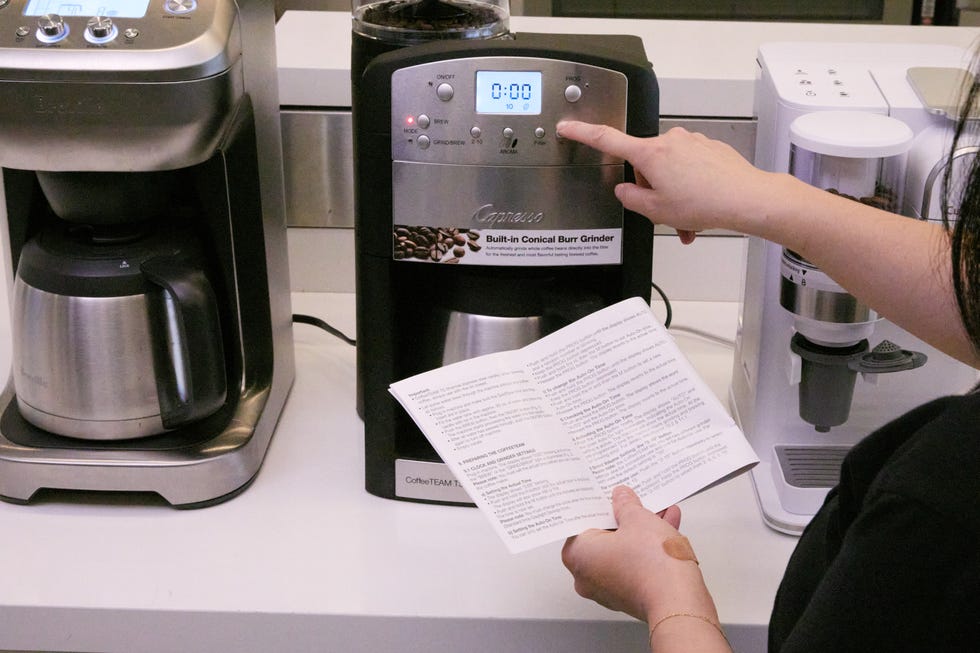 capresso coffeeteam ts coffee maker brewing coffee with a person reading the instruction manual