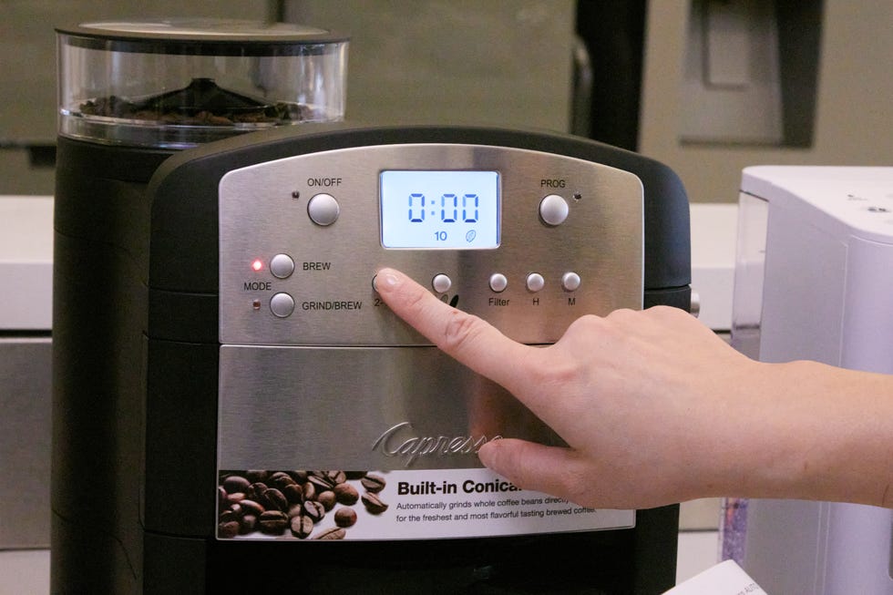 finger pushing button on a coffee maker