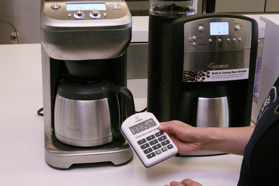 breville coffee maker brewing coffee with a hand holding a timer