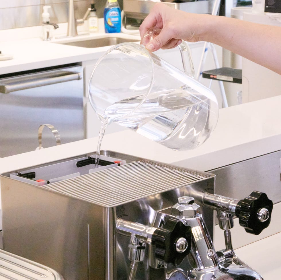 best manual espresso machines hand holding pitcher pouring water into an espresso machine