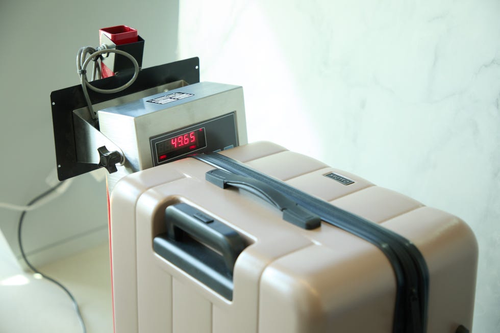 luggage being weighed at 49.65 pounds on a calibrated scale