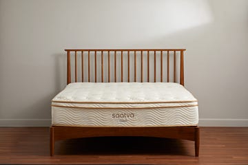 a white and gold mattress from saatva on a bed frame