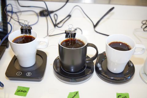 three mugs on warming plates with two showing a binder clip holding a thermocouple in place as part of the heat retention testing