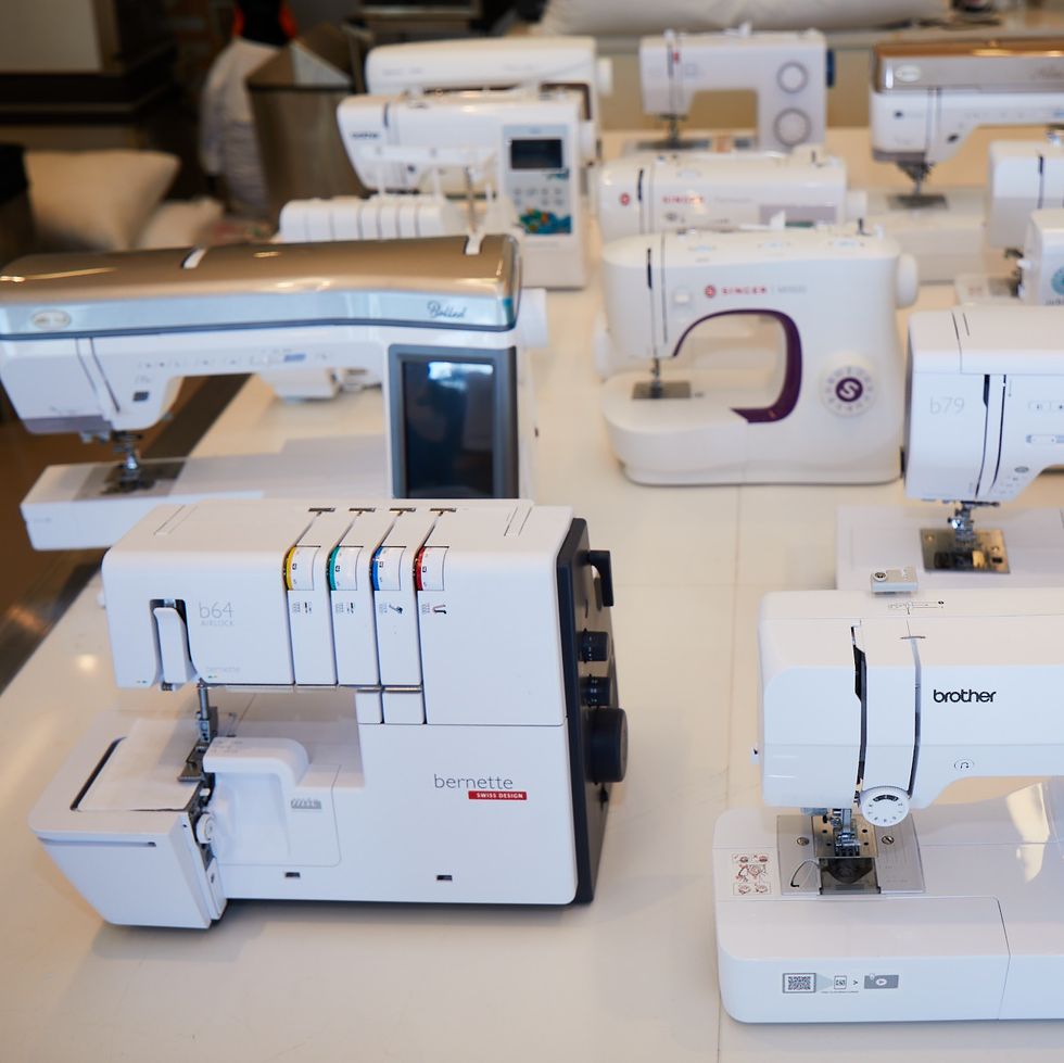 a group of sewing machines, sergers and embroidery machines on a large white table in the good housekeeping institute as part of our best embroidery machine testing