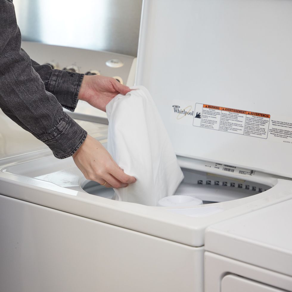 a person holding a towel over a washing machine