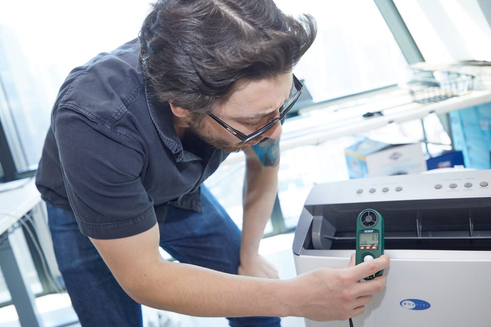 an expert measures the air speed coming off a portable air conditioner