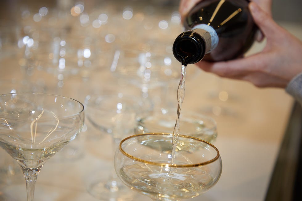 a person pouring wine into glasses