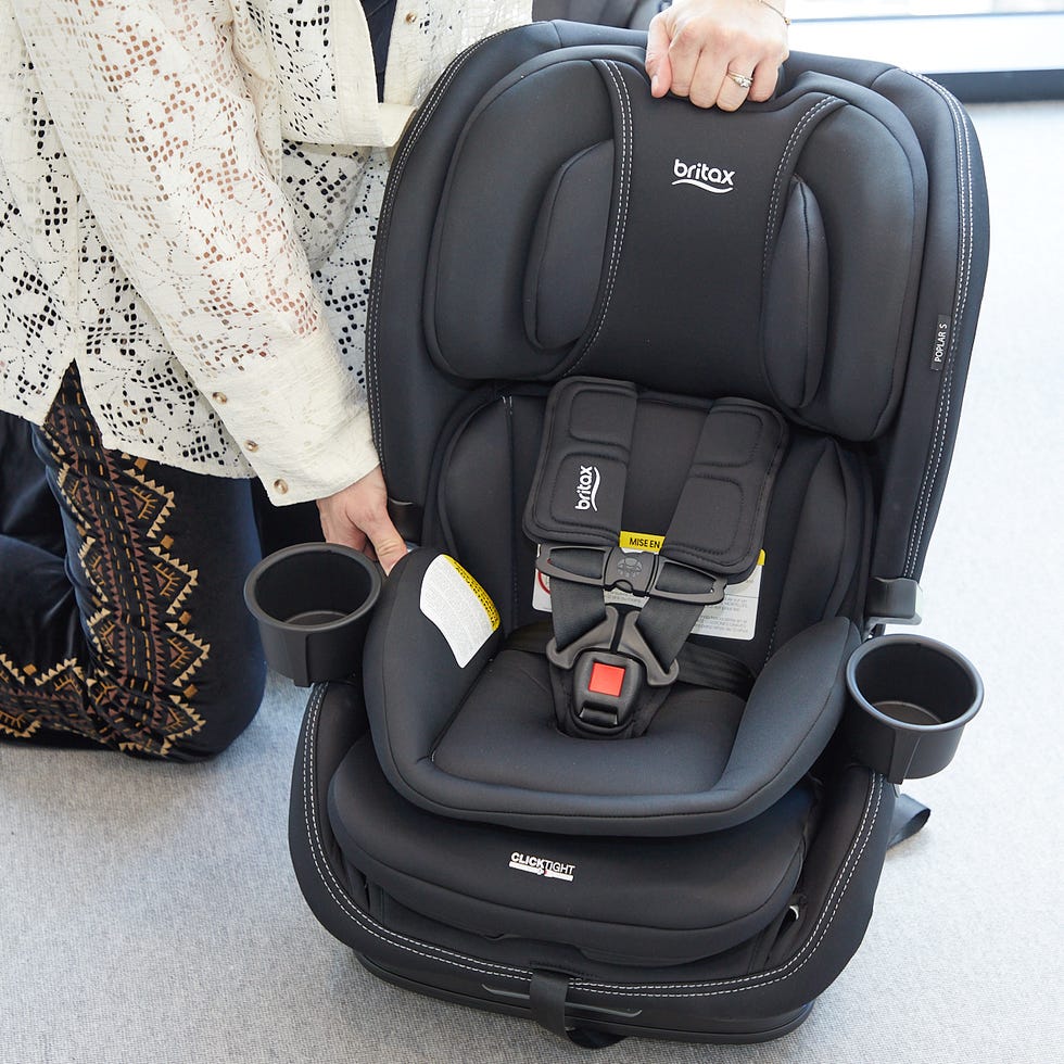 testing the Britax Polar S car seat a person in a white shirt and black pants lifts the headrest of the britax poplar car seat