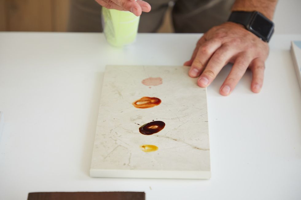 a tester removes wine, ketchup, chocolate and mustard from a porcelain countertop sample to measure its stain resistance
