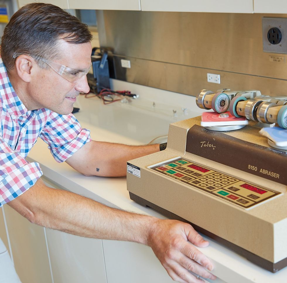 a tester uses an abrasion machine to measure paint durability