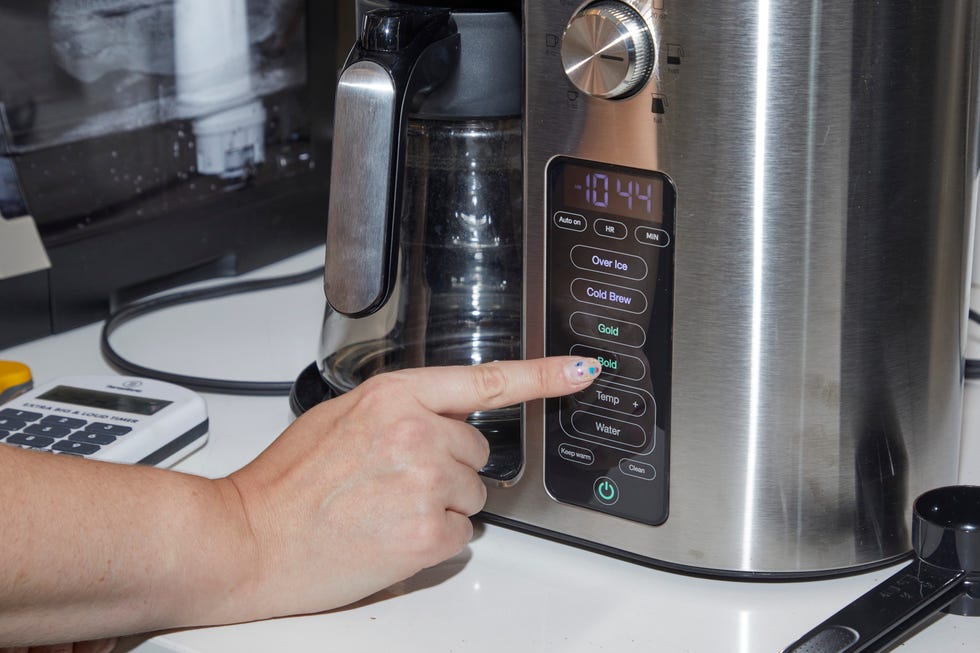 hand pressing a button on a coffee maker