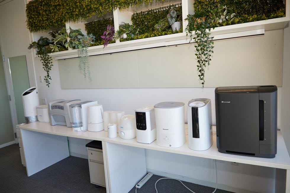 a workspace featuring a white table with a variety of home appliances, including humidifiers, purifiers, and water dispensers