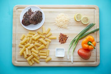 variety of produce, meat and pasta on a cutting board and a blue background for good housekeeping meal delivery testing