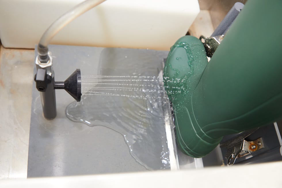 a green waterproof boot is positioned over a sink where water is being sprayed from a nozzle