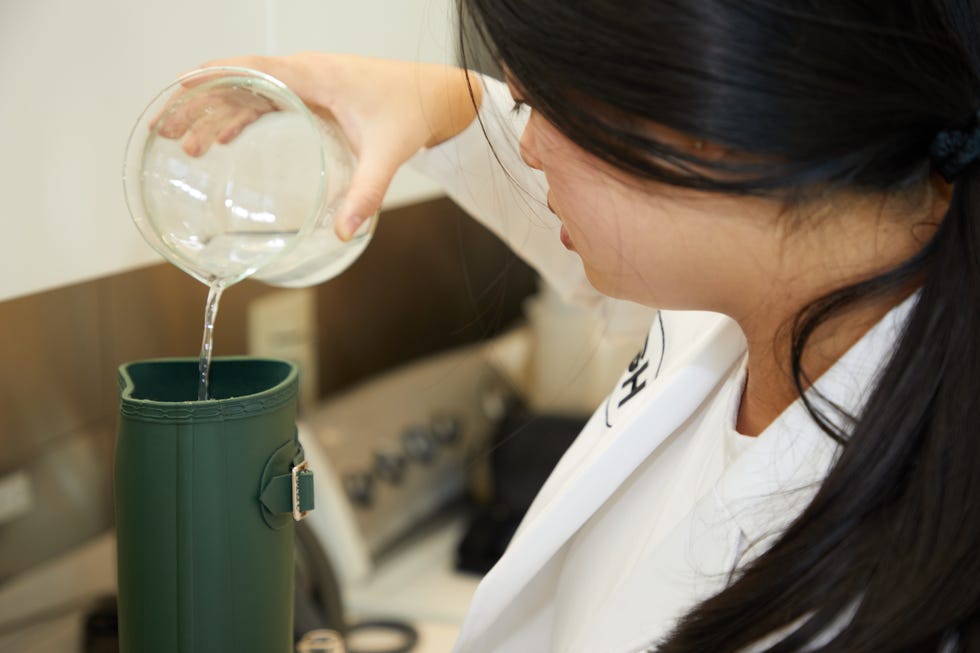 a woman pouring a liquid into a rain boot, good housekeeping's testing for the best rain boots for women