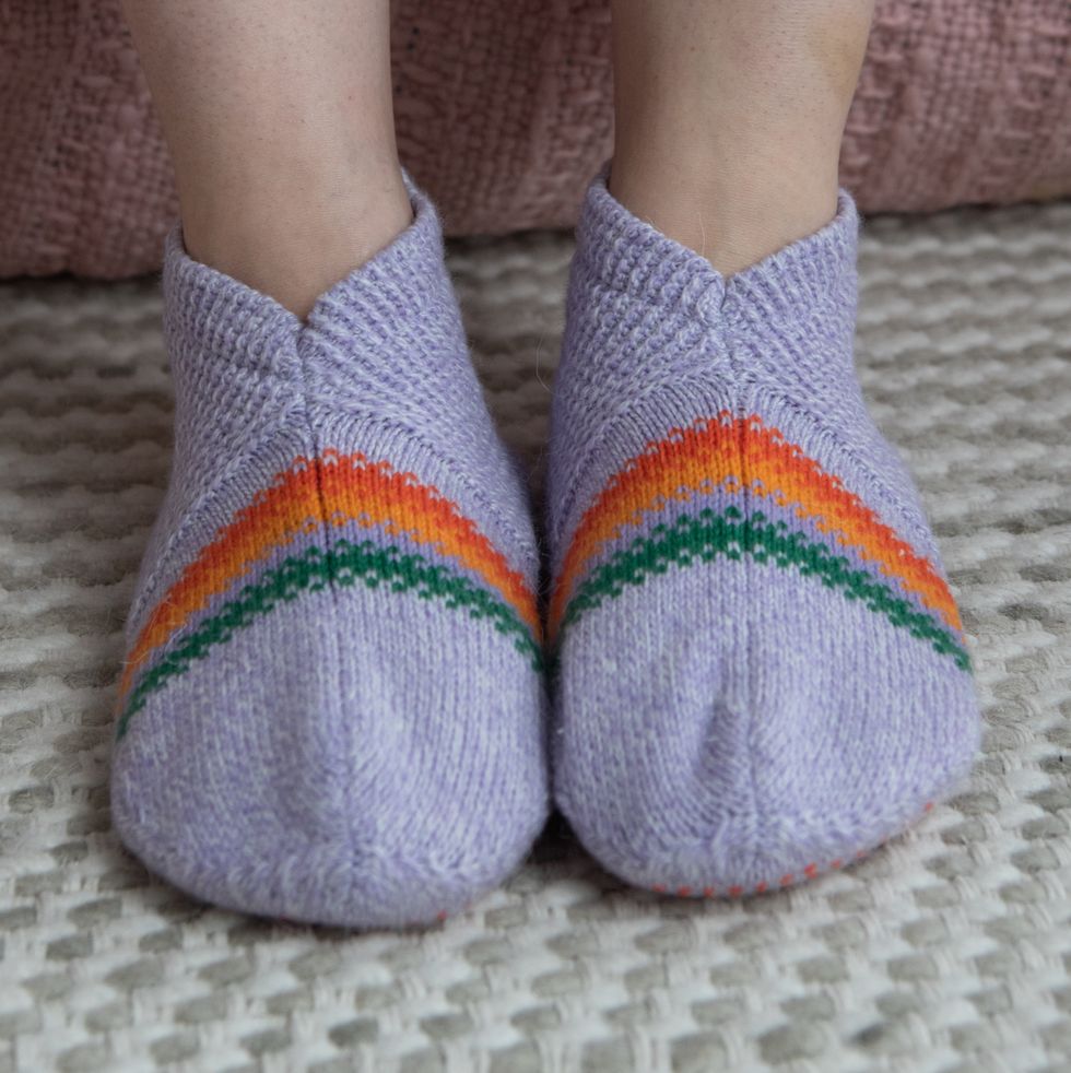 a model wearing purple gripper slippers with orange and green detailing