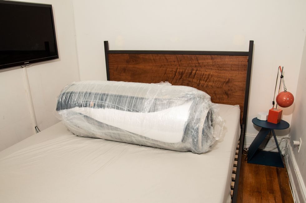 a mattress rolled up in plastic wrap on top of a box spring