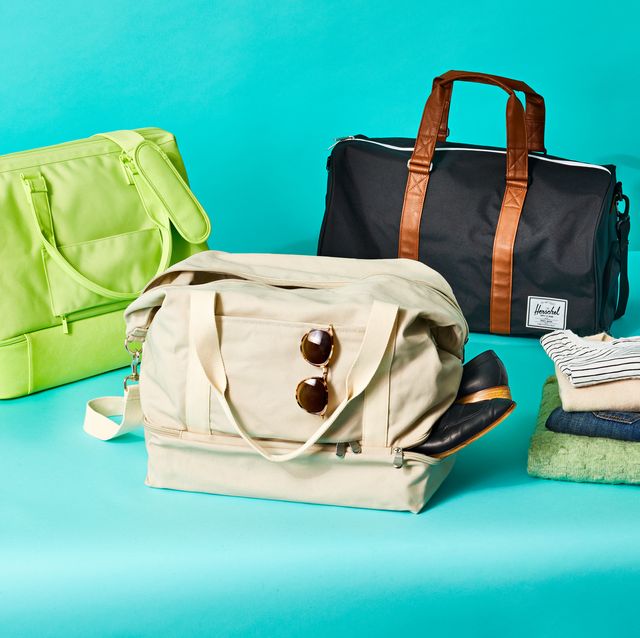 three weekender bags on a blue set with a stack of folded up clothes, good housekeeping's best weekender bags
