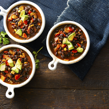 three bowls of hearty fall soup with avocado, beans, and carrots