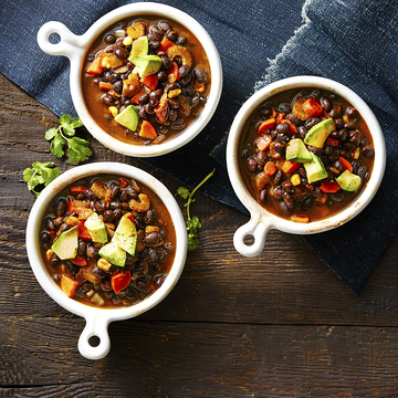 three bowls of hearty fall soup with avocado, beans, and carrots