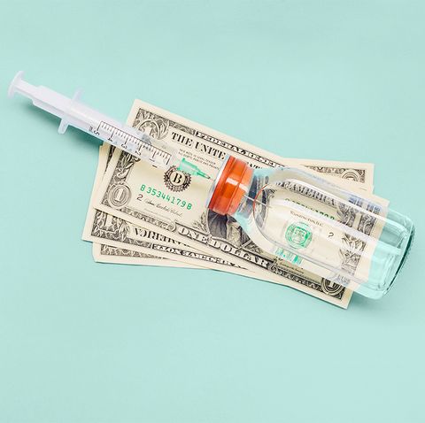 still life of a syringe, ampoule and american dollar banknotes on blue background